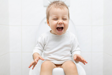 Adorable young child sitting on the toilet