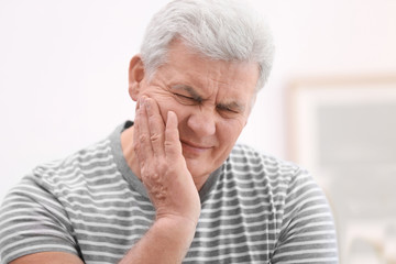 Mature man suffering from toothache at home