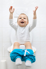 Adorable young child sitting on the toilet - obrazy, fototapety, plakaty