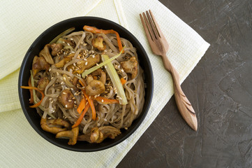 Buckwheat noodles with mushrooms in a black bowl.