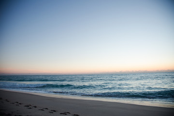 Obraz premium Florida Coast Beach View with Blue and Orange Sky at Sunrise or Sunset with Footprints in the Sand