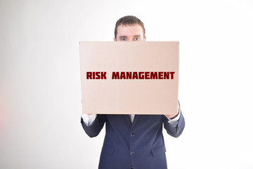 The businessman is holding a box with the inscription:RISK MANAGEMENT