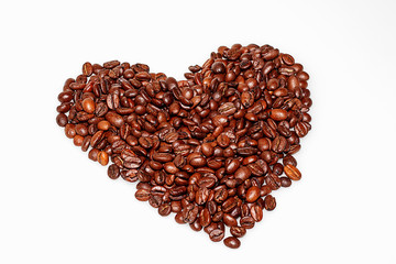 Grains of coffee in the shape of a heart are collected on a white table
