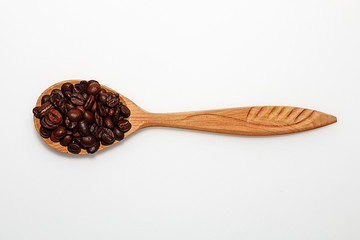 Wooden spoon with coffee beans on white background