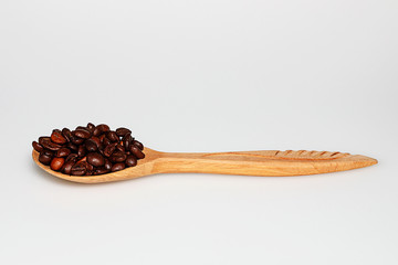 Wooden spoon with coffee beans on white background