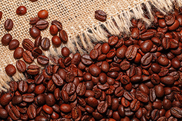 Grains of tasty roasted coffee on the background of cloth burlap