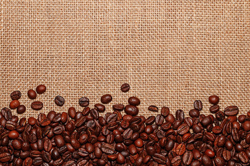 Grains of tasty roasted coffee on the background of cloth burlap
