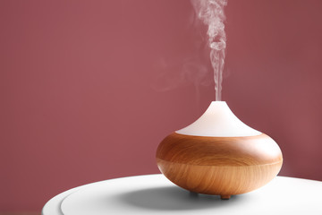 Aroma oil diffuser on table against color background