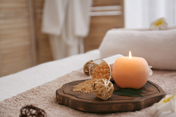 Fototapeta na wymiar Burning candle and sea salt on massage table in spa salon, closeup
