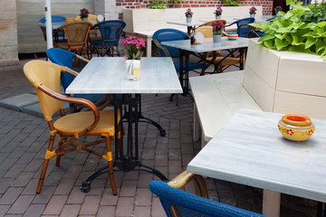 Tables and wooden chairs in a typical european open air restaurant.
