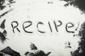 Flour on a black table, an inscription recipe.