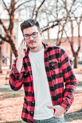 Outdoor portrait of modern young man with mobile phone in park