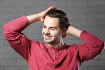 Portrait of young man with beautiful hair on brick wall background