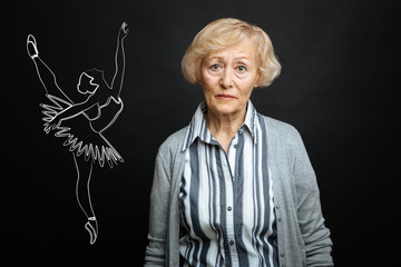 Senior ballerina. Calm sad senior woman looking unhappy while standing alone and remembering her amazing career of a ballerina © zinkevych
