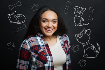 Cute pet. Excited young cheerful woman smiling and feeling happy while coming to a pet shop and...