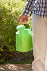 man gardener holding watering can in garden