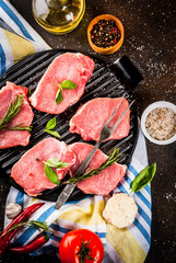 Raw meat, pork steaks with spices, herbs, olive oil, dark background on grill pan, top view, copy space