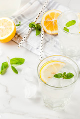Summer refreshing drinks, mojito or lemonade with fresh mint, slices of lemon, ice, on a light background. copy space