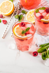 Summer refreshing drinks, fruit and berry raspberry mojito or lemonade with fresh mint, frozen raspberries, slices of lemon, ice, on a light background. copy space