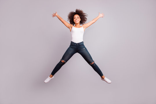 Full length, full size, fullbody portrait of cheerful crazy successful confident lucky charming pretty girl jumping with open hands and legs like star figure, isolated on grey background