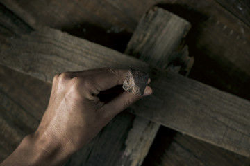man driving a nail on a wooden cross