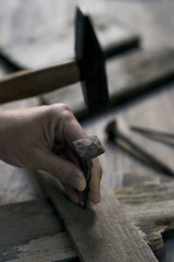 man driving a nail on a wooden cross