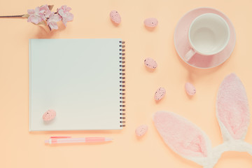 Easter holiday background with notebook and pen, cup for coffee, bunny ears and easter eggs