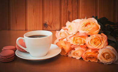 Cup of coffee with bouquet of pink roses flowers. Selective focus.