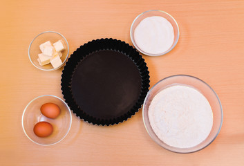 Flour, eggs, sugar, butter and form for baking cake. Top view.