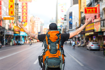 Obraz premium Backpacker man raising his arm in chinatown in bangkok, thailand