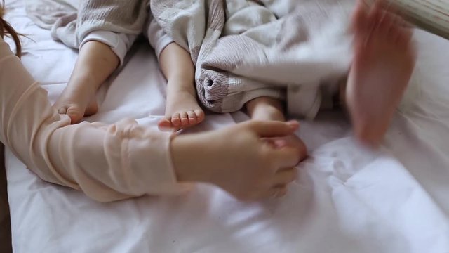 Mom tickled the legs of the children covered with a blanket