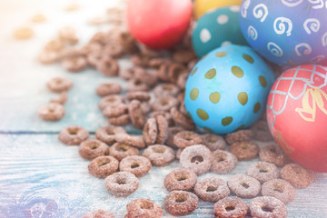 Colorful Easter eggs and sweet corn rings on wooden background. happy Easter