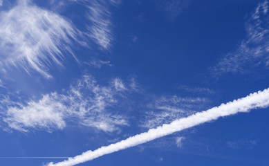 Fototapeta na wymiar Skyscape: Cloudscape with a large contrail in front of a second, higher contrail and thin and wispy cirrus clouds over Eastern Thuringia in September