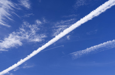 Skyscape: Cloudscape with a large contrail in front of a second, higher contrail and thin and wispy cirrus clouds over Eastern Thuringia in September
