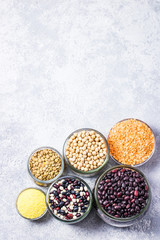 Colorful beans in glass jars on stone background. Top view, space for text.