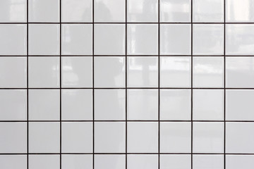 Wall of white glossy tiles with reflection