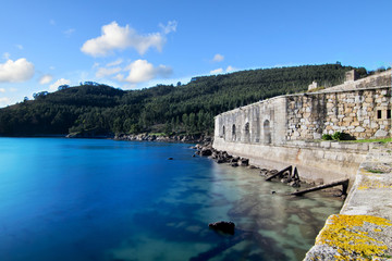 Fototapeta na wymiar Vista de la Ria de Ferrol y un lateral del Castillo de San Felipe, aguas con bonitos tonos azules y cielo con algunas nubes. Un bonito lugar para relajarse
