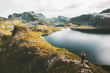Woman alone with backpack hiking on mountain ridge Traveling lifestyle adventure concept active vacations in Norway outdoor lake aerial view