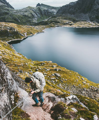 Climber man climbing in mountains holding chains Traveling lifestyle adventure concept hiking wanderlust summer vacations outdoor lake on background