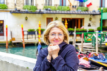 The girl is chilly wrapped in a cloak in winter in Venice, against the background of the canal and...