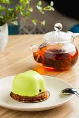 Mini mousse cake apple shaped covered with green mirror glaze on plate