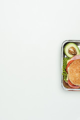 Obraz na płótnie Canvas cropped image of burger with avocado in lunch box isolated on white