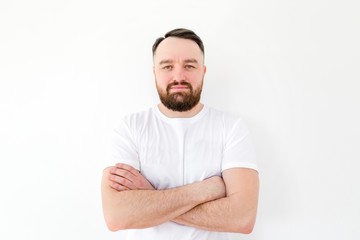 Fototapeta premium Bearded man with his arms crossed standing in casual clothes on a white background