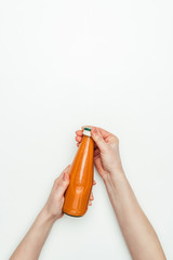 cropped image of woman opening bottle of carrot juice isolated on white