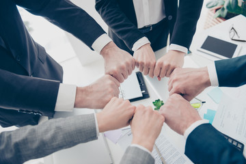 Close up top view cropped photo of experts in elegant classic outfit putting their fists together in a circle standing in work place, station, making ritual, sign, symbol of team, unity, support