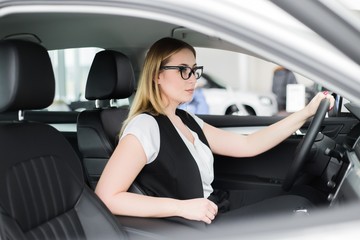 Young girl sitting in glasses driving a new car