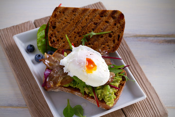 Egg, bacon, smashed white bean and avocado on toast. Sandwich