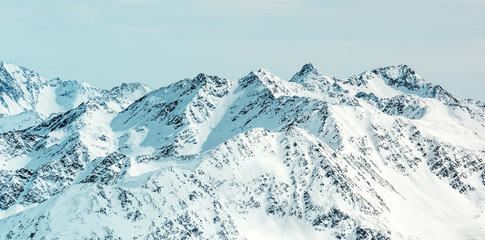 High-Alpine panorama. Snow-capped peaks and cloudy sky