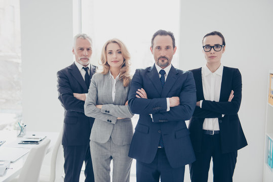Portrait of attractive, concentrated, confident, smart, stylish business persons in suits with crossed arms standing in workplace, workstation, looking at camera