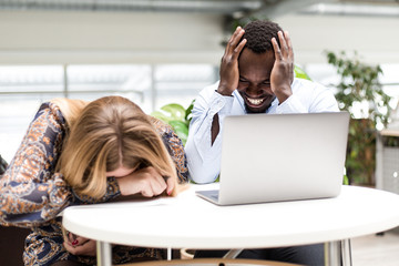 Girl sitting with an African man holding his head in his hands put his head on the table from...